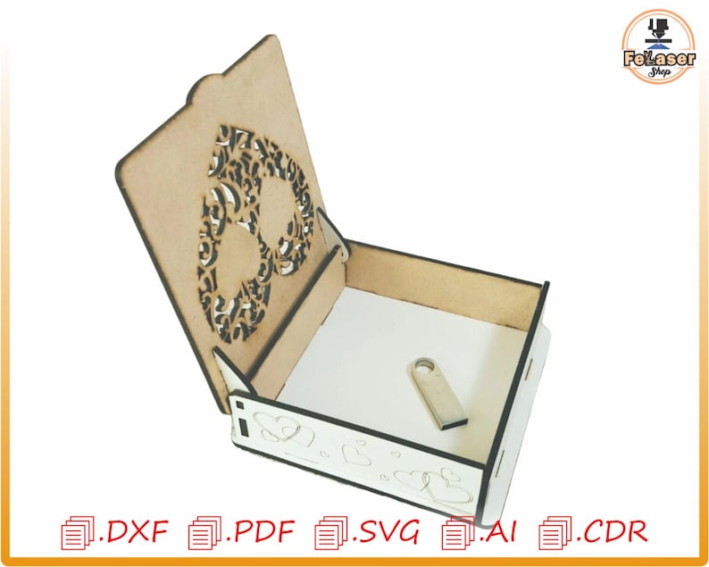 Op de afbeelding: Een houten doos met een scharnierend deksel. Het deksel heeft een uitsparing in de vorm van een hart met een decoratief ontwerp. De doos is open en de binnenkant is leeg.