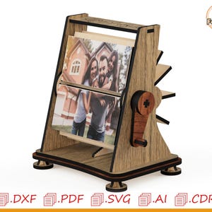 Könnte beinhalten: Ein hölzerner Foto-Display mit Drehmechanismus. Das Display bietet Platz für zwei Fotos und hat einen dekorativen Griff. Der Rahmen besteht aus hellbraunem Holz mit dunklem braunen Zierleisten. Die Fotos zeigen ein Paar und eine Gruppe von Personen.