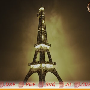 May include: A detailed wooden model of the Eiffel Tower with lights illuminating the structure. The model is lit from within, casting a warm glow. The model is on a dark background.