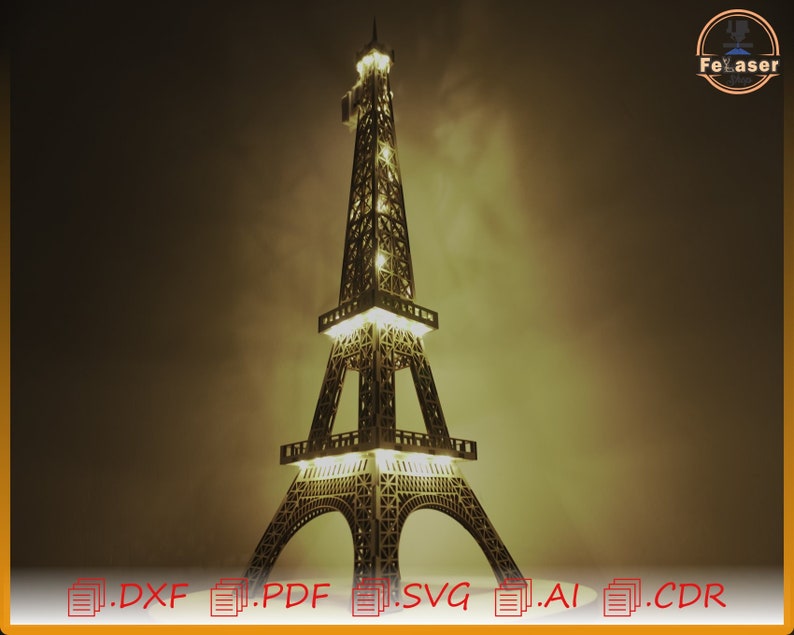 May include: A detailed wooden model of the Eiffel Tower with lights illuminating the structure. The model is lit from within, casting a warm glow. The model is on a dark background.