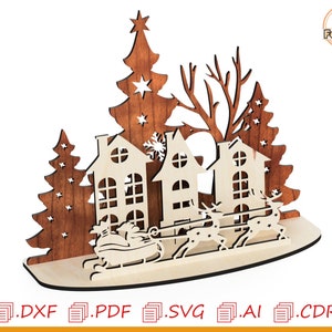 May include: A laser cut wooden Christmas scene with three houses, two Christmas trees, and a sleigh pulled by reindeer. The houses are decorated with windows and a chimney. The trees are decorated with stars. The sleigh is filled with presents.