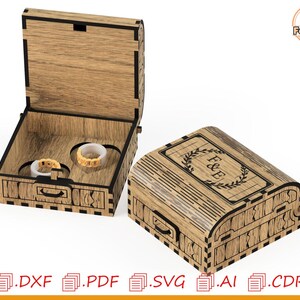 May include: Wooden ring box with a hinged lid, open to reveal two ring slots. The closed box features a decorative design with the initials "F & E" inside a laurel wreath. The box is made of light brown wood with dark brown accents.