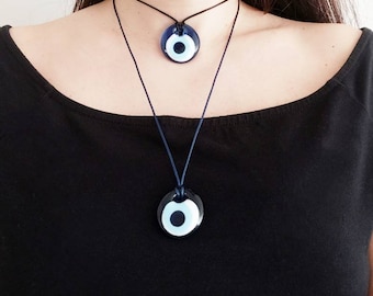 Pode incluir: Dois colares de olho turco azul com cordões pretos. O colar maior está pendurado mais baixo do que o colar menor.