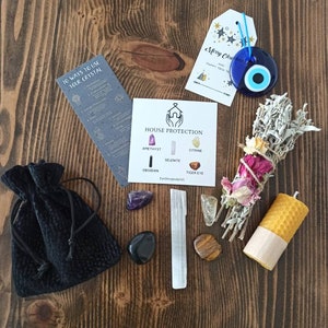 May include: A house protection kit containing crystals, a sage smudge stick, a candle, and a small black pouch. The crystals include amethyst, selenite, citrine, obsidian, and tiger's eye. The kit also includes a card with the text "House Protection" and a list of the crystals. The card also includes the text "EyeDesignbyLC".