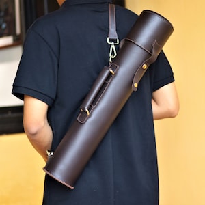 May include: A brown leather carrying case with a shoulder strap. The case has a brass buckle and a handle.