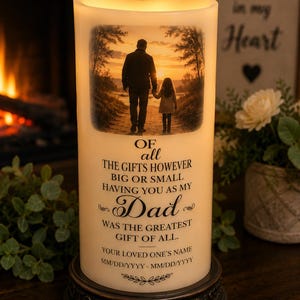 May include: A cylindrical LED candle with a warm glow, featuring a printed photograph of an adult and child walking on a path at sunset. The text reads: OF all THE GIFTS HOWEVER BIG OR SMALL HAVING YOU AS MY Dad WAS THE GREATEST GIFT OF ALL.