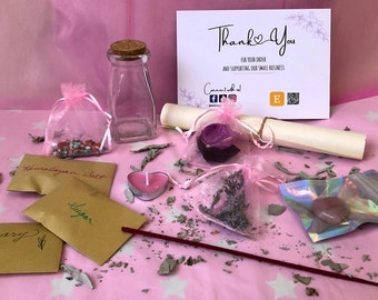 May include: A pink and white thank you card with a heart and the text "Thank You" for your order and supporting our small business.  The card is surrounded by a variety of items including a clear glass bottle, a pink and white bag with crystals, a pink candle, a brown paper bag with the text "Himalayan Salt", a brown paper bag with the text "Sugar", a brown paper bag with the text "Mary", a pink and white bag with dried lavender, a pink and white bag with a dried rose, a rolled up piece of parchment paper, a pink incense stick, and a pink and white crystal.