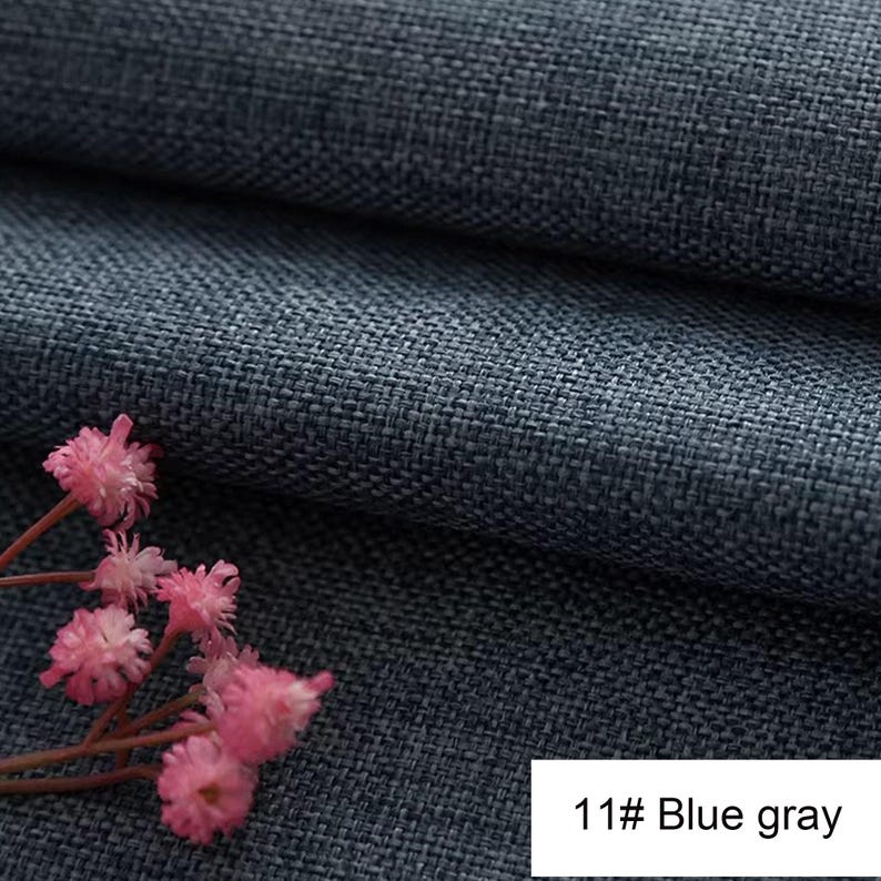 May include: A dark blue-grey fabric with a visible woven texture and a folded appearance. A small cluster of delicate pink flowers with thin stems is positioned in the lower left corner. A white rectangular label displays the text 11# Blue gray.
