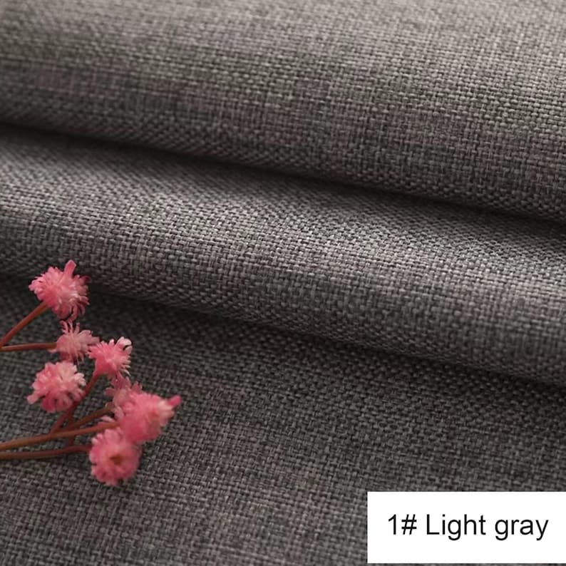 May include: A light grey fabric with a visible woven texture and a folded appearance. A small cluster of delicate pink flowers with thin stems is positioned in the lower left corner. The text 1# Light grey is printed in the bottom right corner.