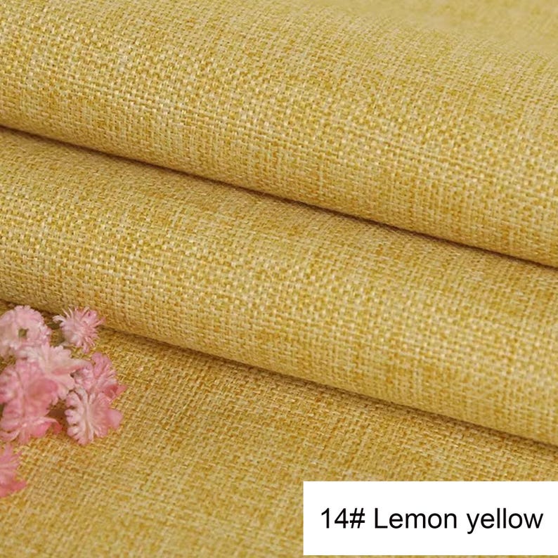 May include: A folded piece of lemon yellow fabric with a visible woven texture. The material features a consistent, coarse weave pattern throughout. A small cluster of light pink flowers is visible in the lower left corner. Text reads 14# Lemon yellow.