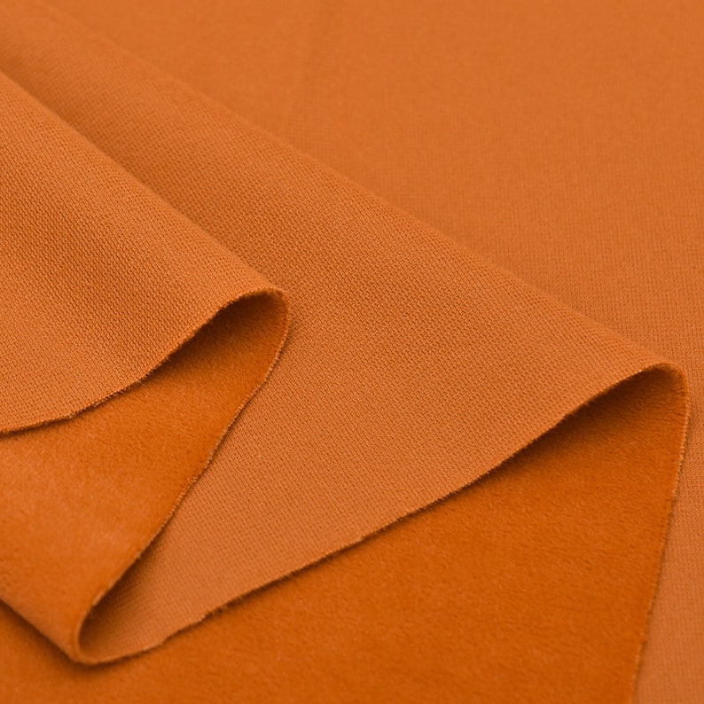 May include: Close-up of a folded piece of orange fabric. The fabric has a textured surface and a soft, fuzzy feel.