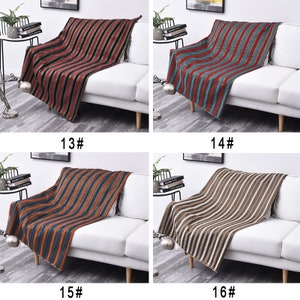 May include: Four striped throw blankets displayed on white sofas. The blankets are in different color combinations: red and black, blue and red, orange and blue, and brown and white.