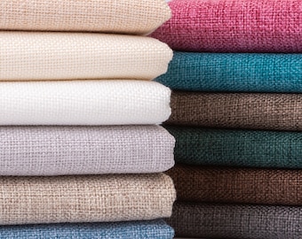 May include: A stack of fabric swatches in various colors and textures, including beige, white, gray, brown, teal, and pink. The swatches are folded neatly and arranged in a row.