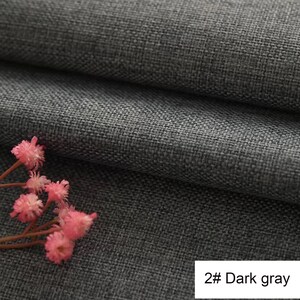 May include: A dark grey fabric with a visible woven texture and a folded layer, accompanied by a small cluster of delicate pink flowers. A white rectangular label in the bottom right corner displays the text 2# Dark grey in black font.