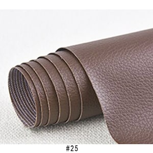 Puede incluir: Un rollo de tela de imitaci&oacute;n de cuero marr&oacute;n. La tela tiene una superficie texturizada que se asemeja al cuero. #25