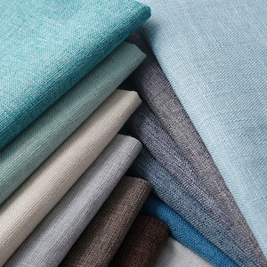 May include: A stack of fabric swatches in various shades of blue, gray, and brown. The swatches are arranged in a fan shape, with the lightest colors at the top and the darkest colors at the bottom.