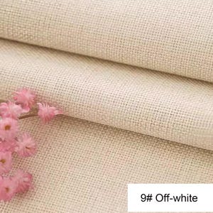 May include: A piece of off-white fabric with a visible woven grid texture, featuring a cluster of small, light pink flowers on the left side. A white rectangular label in the bottom right corner displays the text 9# Off-white.