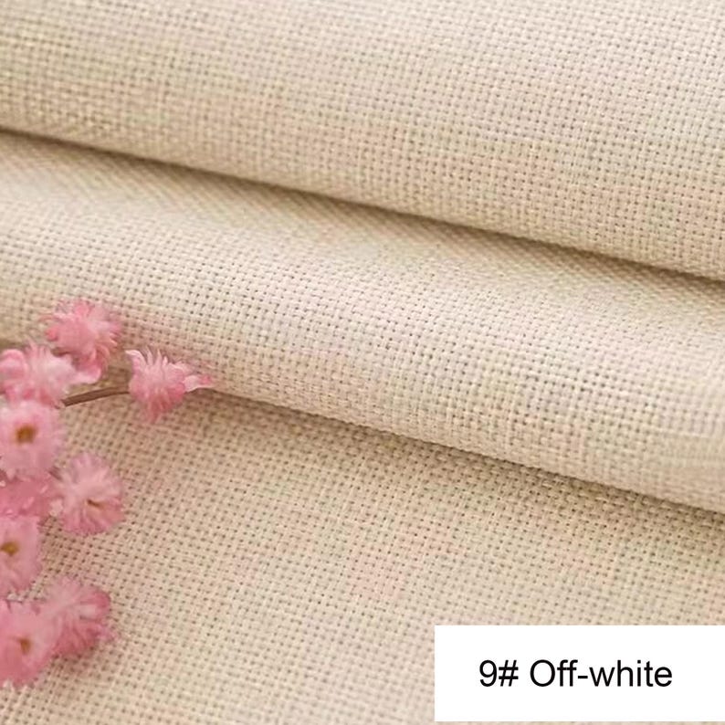 May include: A piece of off-white fabric with a visible woven grid texture, featuring a cluster of small, light pink flowers on the left side. A white rectangular label in the bottom right corner displays the text 9# Off-white.