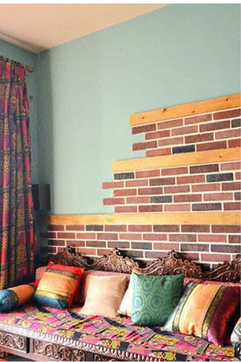 May include: A wooden couch with colorful patterned cushions and throw pillows. The couch is in front of a wall with a brick pattern made from faux brick panels.