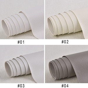 Puede incluir: Cuatro rollos de piel sint&eacute;tica en diferentes colores. El primer rollo es blanco, el segundo es blanquecino, el tercero es gris claro y el cuarto es gris. Cada rollo est&aacute; etiquetado con un n&uacute;mero del 1 al 4.