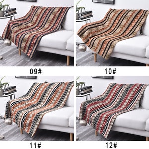 May include: Four different patterned throw blankets in various shades of brown, red, black, and white are draped over white sofas. The blankets have a geometric pattern with stripes and small shapes.