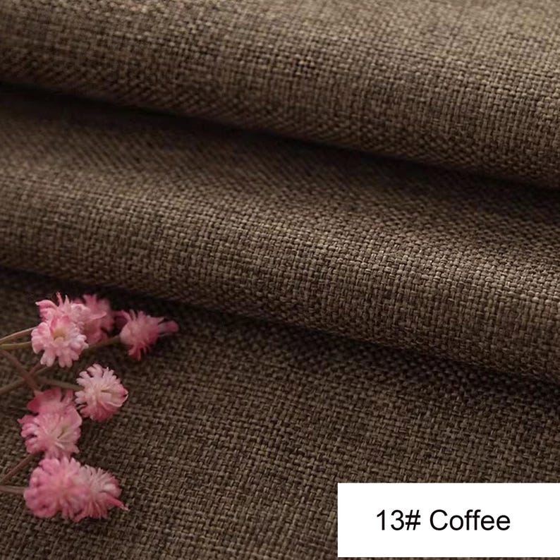 May include: A brown fabric with a visible woven texture, featuring a folded layer and a small cluster of light pink flowers in the corner. A white rectangular label in the bottom right corner displays the text 13# Coffee in black font.
