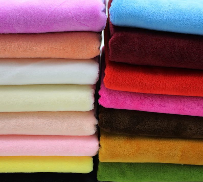 May include: A stack of 15 different colored plush fabrics. The fabrics are arranged in a vertical stack, with the lightest color at the top and the darkest color at the bottom. The colors include pink, peach, white, cream, light pink, dark pink, brown, orange, green, and black.