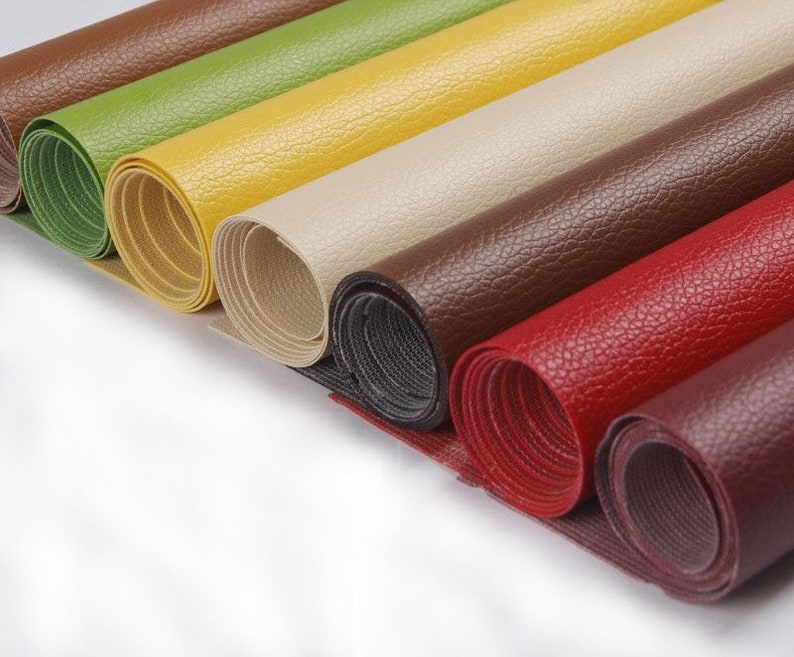 Puede incluir: Una colecci&oacute;n de muestras de tela enrolladas en varios colores, incluyendo marr&oacute;n, verde, amarillo, beige, rojo y burdeos. La tela tiene una apariencia texturizada, similar al cuero.