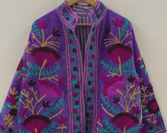 May include: A purple velvet jacket with intricate floral embroidery in shades of pink, green, and gold. The jacket has a mandarin collar and a striped lining, creating a bohemian aesthetic.