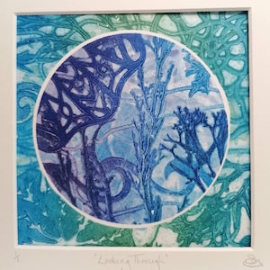 Puede incluir: Una impresión enmarcada de una obra de arte abstracta azul y verde con el título "Looking Through". La obra de arte presenta un diseño circular con un fondo azul y blanco y un borde verde.