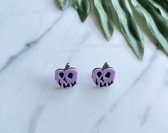 May include: A pair of purple and black poison apple earrings. The earrings are shaped like apples with a skull face and dripping purple poison.