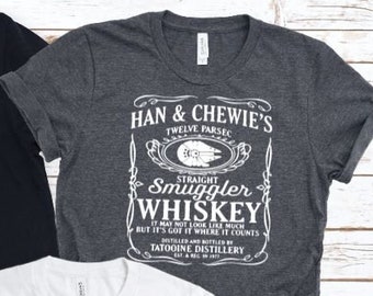 May include: Three t-shirts with a Star Wars themed design. The design features a black and white graphic of a whiskey bottle label with the text "Han & Chewie's Twelve Parsec Straight Smuggler Whiskey It may not look like much but it's got it where it counts Distilled and Bottled by Tatooine Distillery"