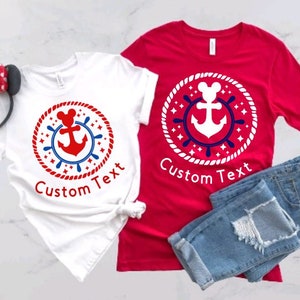 May include: Two t-shirts with a nautical themed design featuring a white anchor with a red and blue rope circle around it. The design also includes a Mickey Mouse head. The text "Custom Text" is printed on both shirts.