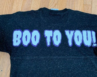 Może przedstawiać: Czarny T-shirt z nadrukiem "BOO TO YOU!" w jasnoniebieskim i fioletowym kolorze.