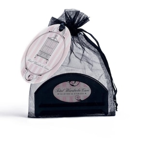 May include: A black and white oval tag with the text "Total Wardrobe Care" and a small illustration of a dresser. The tag is attached to a black mesh bag with a black plastic hanger inside. The hanger has the text "Total Wardrobe Care - Valeting & Storage" on it.