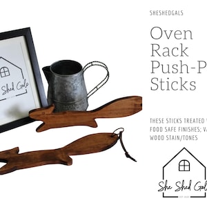 May include: Two wooden oven rack push-pull sticks, shaped like a squirrel tail, with a rustic brown finish. The sticks are treated with food-safe finishes and are available in various wood stains and tones. The image also includes a metal watering can and a framed sign that reads "She Shed Gals".