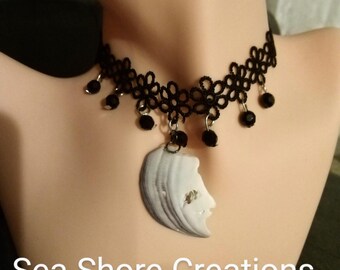 Può includere: Girocollo in pizzo nero con perline nere pendenti e un ciondolo a forma di volto scolpito in una conchiglia. Il testo "Sea Shore Creations" è in basso nell'immagine.