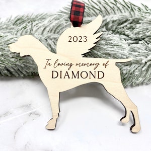 May include: Wooden Christmas ornament shaped like a dog with angel wings. The ornament is engraved with "In loving memory of DIAMOND" and the year "2023".