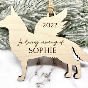 German Shepherd with angel wings memorial ornament. Ornament is made of wood with, “In loving memory of”, dog’s name, and year engraved on it. Ornament is hung with a jute twine.