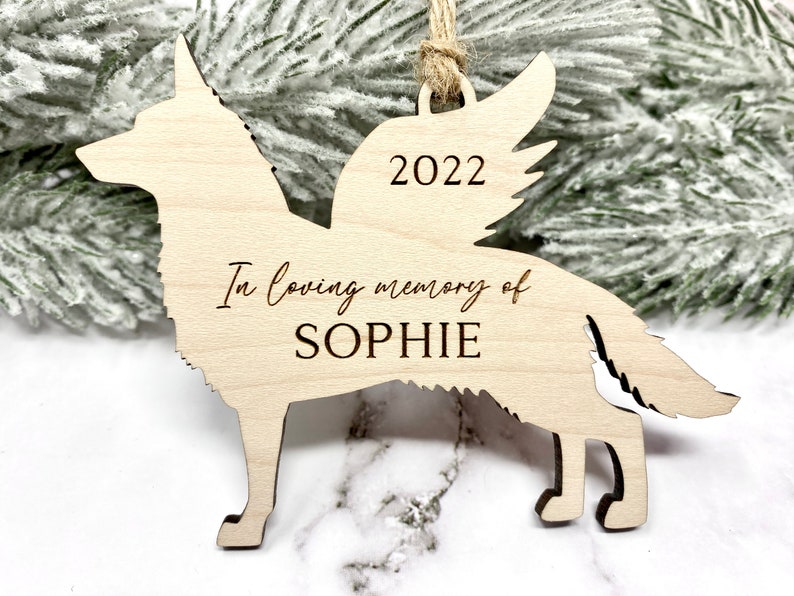 German Shepherd with angel wings memorial ornament. Ornament is made of wood with, “In loving memory of”, dog’s name, and year engraved on it. Ornament is hung with a jute twine.