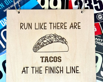 May include: Wooden sign with the text "Run like there are tacos at the finish line." A black and white illustration of a taco is above the text.