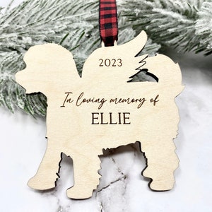May include: Wooden Christmas ornament shaped like a dog with the text "In loving memory of ELLIE" and the year "2023" engraved on it.