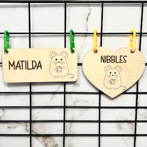 Könnte beinhalten: Zwei hölzerne Haustier-Namensschilder mit einem Maus-Design. Ein Schild ist rechteckig und sagt "MATILDA" und das andere ist herzförmig und sagt "NIBBLES".