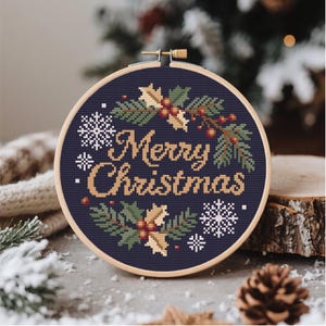 May include: A cross-stitch embroidery hoop with a navy blue background and the words "Merry Christmas" in gold. The design includes snowflakes, holly, and pine branches. The wooden hoop is approximately 6 inches in diameter.