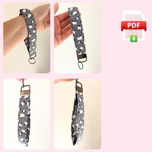 May include: A gray and white fabric key chain with a sheep pattern. The key chain has a silver metal ring.