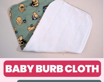 May include: Baby burb cloth with a Winnie the Pooh pattern on a green background. The cloth is made of soft, absorbent material. The text "Baby Burb Cloth" is displayed in a red banner, with "Sewing Pattern and Guide!" in a green banner.