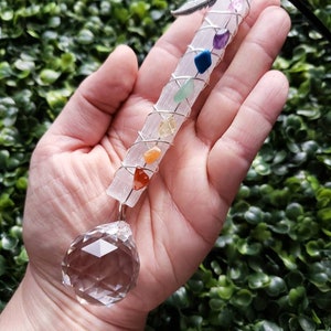 Puede incluir: Una varita de selenita blanca envuelta en alambre y adornada con siete piedras de chakra. Una bola de cristal transparente cuelga de la parte inferior de la varita.