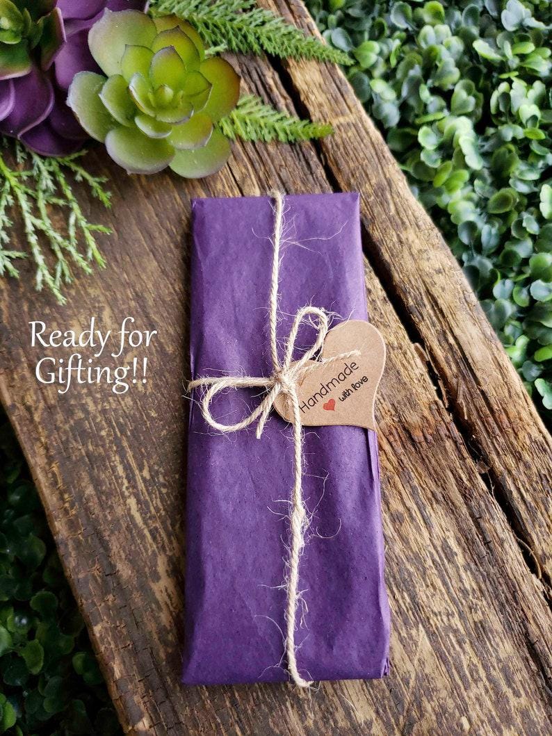 May include: A purple gift bag tied with twine and a brown heart-shaped tag that says "Handmade with love".