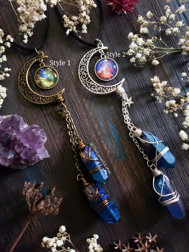 Puede incluir: Dos collares de media luna con cabujones de galaxia y colgantes de cristal azul. El collar de la izquierda tiene una media luna de bronce y el collar de la derecha tiene una media luna de plata. El texto "Style 1" y "Style 2" es visible en la imagen. El texto "@TheLunarlyLotus" tambi&eacute;n es visible en la imagen.