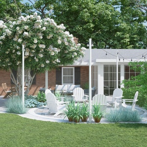 May include: A backyard patio with white patio furniture, a fire pit, and a white swing hanging from a tree. The patio is surrounded by green grass and trees.